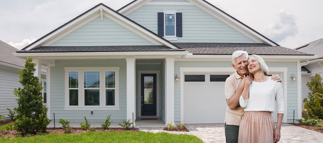 Happy senior couple standing in front of their modern manufactured home